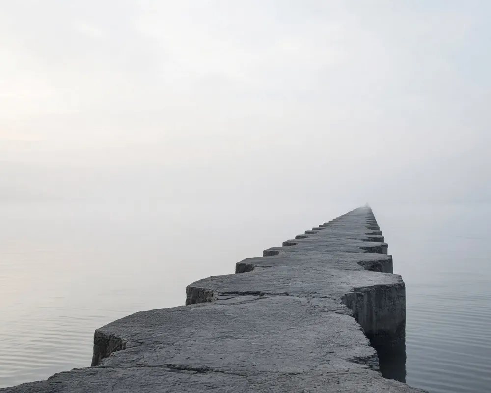 Editorial photograph of a pier extending into mist
